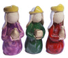 3 ceramic figures of the 3 wise men in purple, dark green, and red shiny glaze on pale ceramic. each wise man has a yellow crown and they all hold gifts with gold glaze.