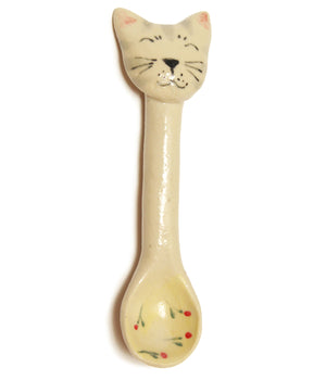 a small pale coloured ceramic spoon with a coloured bowl and the face of a cat on the end of the handle